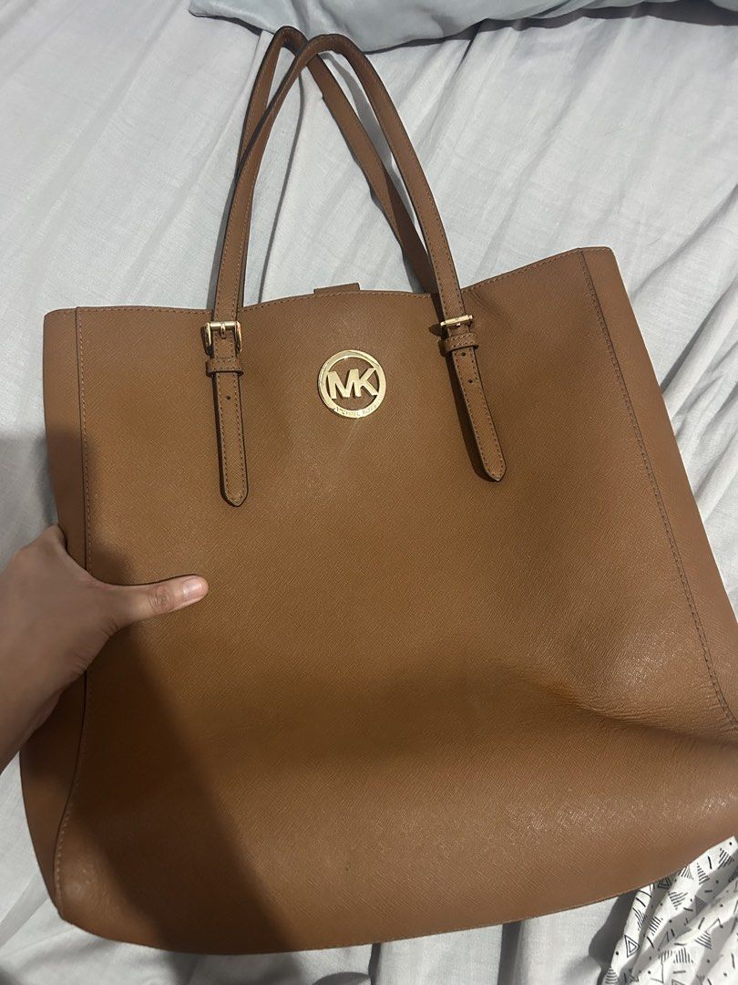 Michael Kors Brown Leather Tote Bag (Category: Tote Bags) located in Makati City. Submitted by swifttttt (Listing ID 1449165064, Image 2). Description: - Classic brown leather Michael Kors tote bag - Gold MK logo hardware on the front - Adjustable shoulder straps with buckle detail - Spacious interior, ideal for everyday use - Simple, chic, and versatile design for work or casual outings.