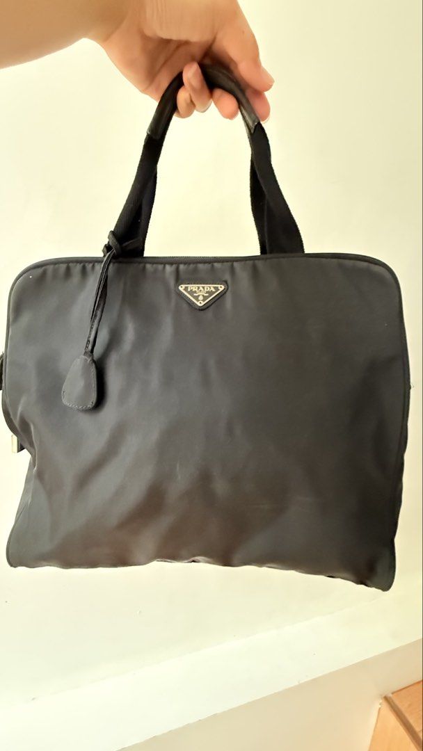 Prada Handbag (Category: Luxury Bags & Wallets) located in Malolos. Submitted by flapnbloom.ph (Listing ID 1449137587, Image 1). Description: - Authentic Prada nylon handbag - Features the iconic Prada triangle logo - Comes with a small padlock and key - Handles show some signs of wear - Zippers are in good working condition - Large size.