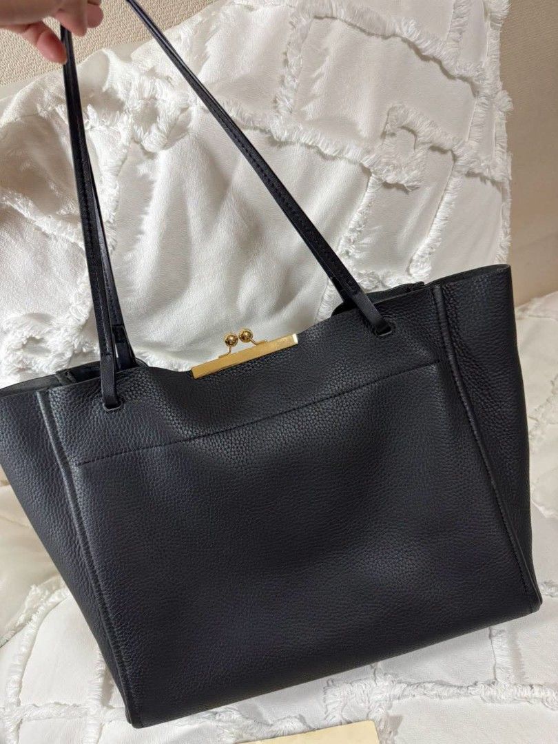 The Marc Jacobs Black Leather Tote Bag (Category: Luxury Bags & Wallets) located in Bulacan. Submitted by vintage_purge (Listing ID 1449135597, Image 3). Description: - Brand: The Marc Jacobs - Material: Black pebbled leather - Closure: Gold-tone clasp at the top - Features: Large embossed logo on the front - Interior: Spacious, ideal for essentials - Style: Great everyday bag.