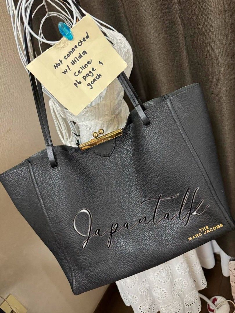 The Marc Jacobs Black Leather Tote Bag (Category: Luxury Bags & Wallets) located in Bulacan. Submitted by vintage_purge (Listing ID 1449135597, Image 2). Description: - Brand: The Marc Jacobs - Material: Black pebbled leather - Closure: Gold-tone clasp at the top - Features: Large embossed logo on the front - Interior: Spacious, ideal for essentials - Style: Great everyday bag.