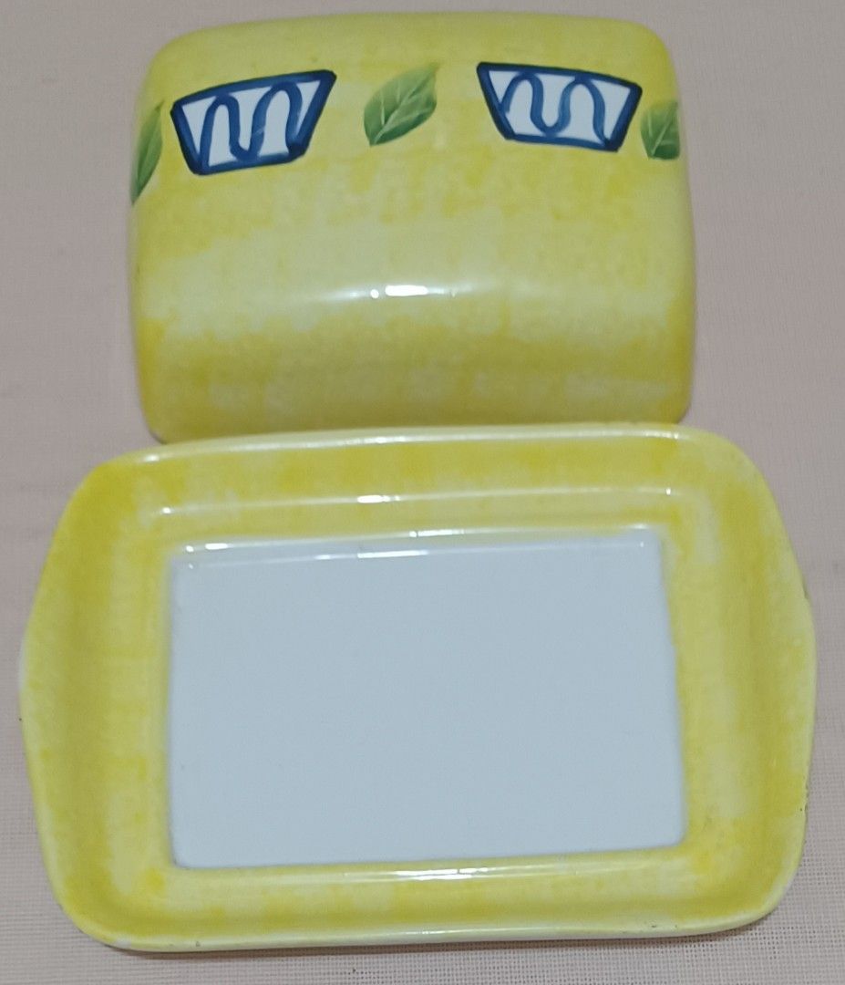 🧈 Hand-Painted Ceramic Butter Dish (Category: Other Kitchenware & Tableware) located in Quezon City. Submitted by wjmae (Listing ID 1449429551, Image 3). Description: Item Details: - Design: Bright yellow marbled finish with hand-painted blue geometric accents + green leaf details; classic country/kitchen style ​ - Size: Approx 6.75 in × 5.25 in base, fits standard 250g/1lb butter blocks perfectly ​ - Material: Glossy glazed ceramic, easy to cle