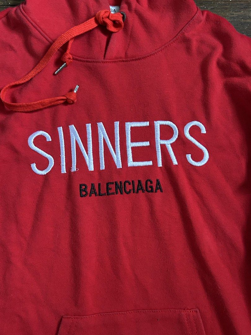 Balenciaga Sinners Red Hoodie (Category: Hoodies) located in Pasay City. Submitted by julesmarts (Listing ID 1449454430, Image 2). Description: - Authentic Balenciaga Sinners Hoodie in vibrant red. - Features the iconic 'Sinners' text embroidered prominently on the front. - Includes the Balenciaga Paris tag for authenticity. - Adjustable drawstrings for the hood. - Convenient kangaroo pocket on the front..