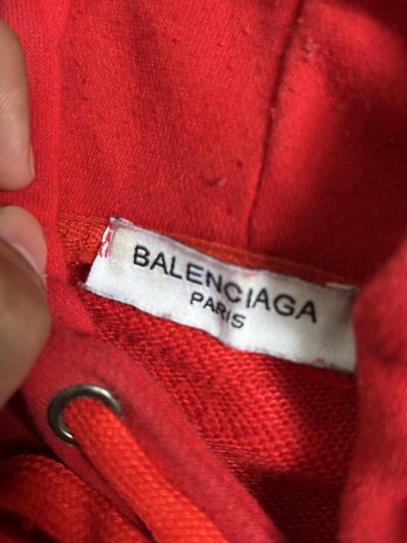 Balenciaga Sinners Red Hoodie (Category: Hoodies) located in Pasay City. Submitted by julesmarts (Listing ID 1449454430, Image 3). Description: - Authentic Balenciaga Sinners Hoodie in vibrant red. - Features the iconic 'Sinners' text embroidered prominently on the front. - Includes the Balenciaga Paris tag for authenticity. - Adjustable drawstrings for the hood. - Convenient kangaroo pocket on the front..