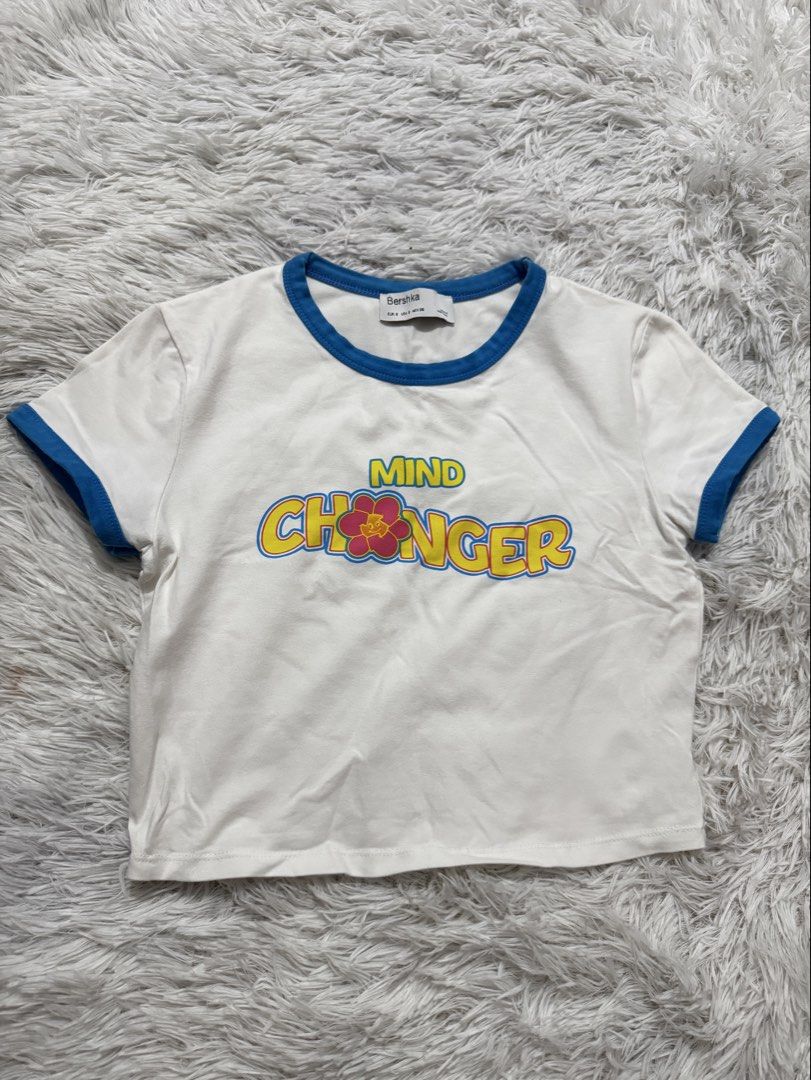 Bershka White Crop Top "Mind Changer" Graphic Tee (Category: Shirts) located in Manila. Submitted by itsyufinds (Listing ID 1449513539, Image 1). Description: - White Bershka crop top - Features "Mind Changer" graphic with a flower - Blue trim detail - Short sleeves - Cropped fit .