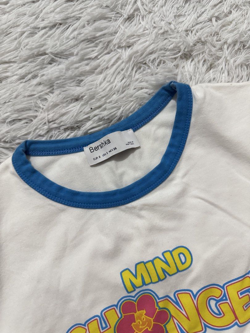 Bershka White Crop Top "Mind Changer" Graphic Tee (Category: Shirts) located in Manila. Submitted by itsyufinds (Listing ID 1449513539, Image 2). Description: - White Bershka crop top - Features "Mind Changer" graphic with a flower - Blue trim detail - Short sleeves - Cropped fit .
