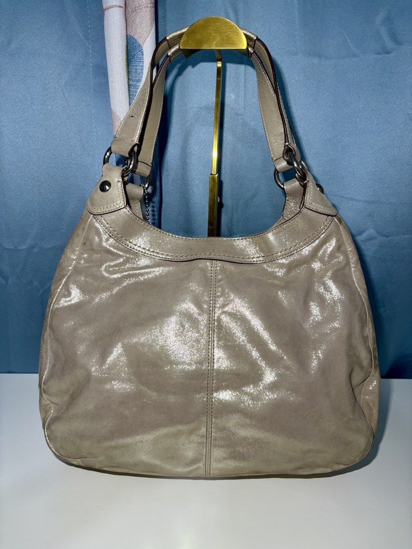 Coach Soho Lynn Hobo Shoulder Bag (Category: Shoulder Bags) located in Pasig City. Submitted by talaversify (Listing ID 1449497486, Image 2). Description: • Authentic Coach Soho Lynn in hobo shoulder shape featuring pleated front accents and a prominent decorative center buckle flap with a magnetic snap closure. • Shimmery, metallic champagne gold cowhide leather in silver-tone hardware. • Multi-compartment interior consisting three main sections