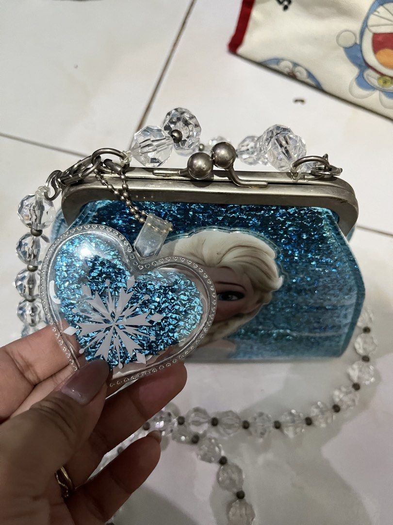 Elsa Frozen Glitter Handbag with Beaded Strap (Category: Purses & Pouches) located in Angono. Submitted by dubibo (Listing ID 1449475284, Image 3). Description: - Cute Elsa handbag with a glittery blue finish. - Features a heart-shaped charm with 'Elsa' on it. - Clear bead strap for a stylish touch. - Blue fabric lining inside. - Ideal gift for any Frozen enthusiast!.