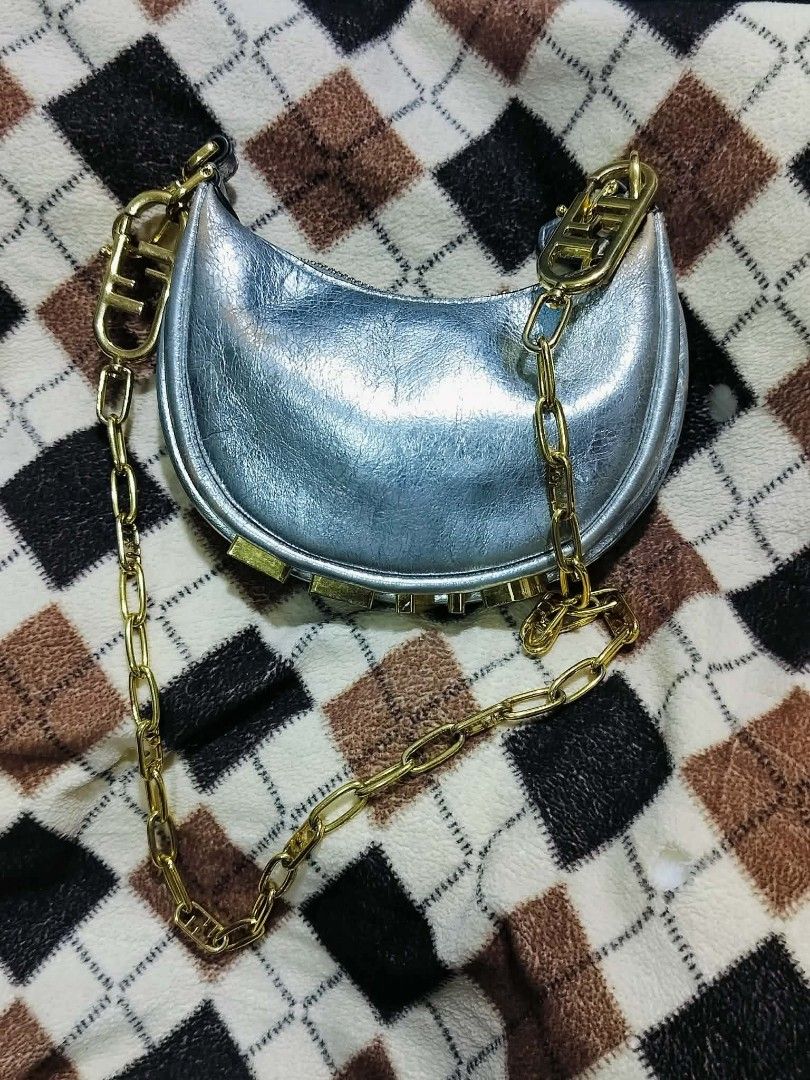 Fendi Moon Baguette Chain Bag Silver Metallic (Category: Luxury Bags & Wallets) located in Manila. Submitted by rose_onlineshop28 (Listing ID 1449424384, Image 1). Description: - Fendi Moon Bag - Color: Silver Metallic - Features iconic Fendi logo on the side - Stylish chain strap with Fendi logo clasp - Unique crescent shape - Interior tag with serial number - Ideal for night outs or adding a statement to your outfit.
