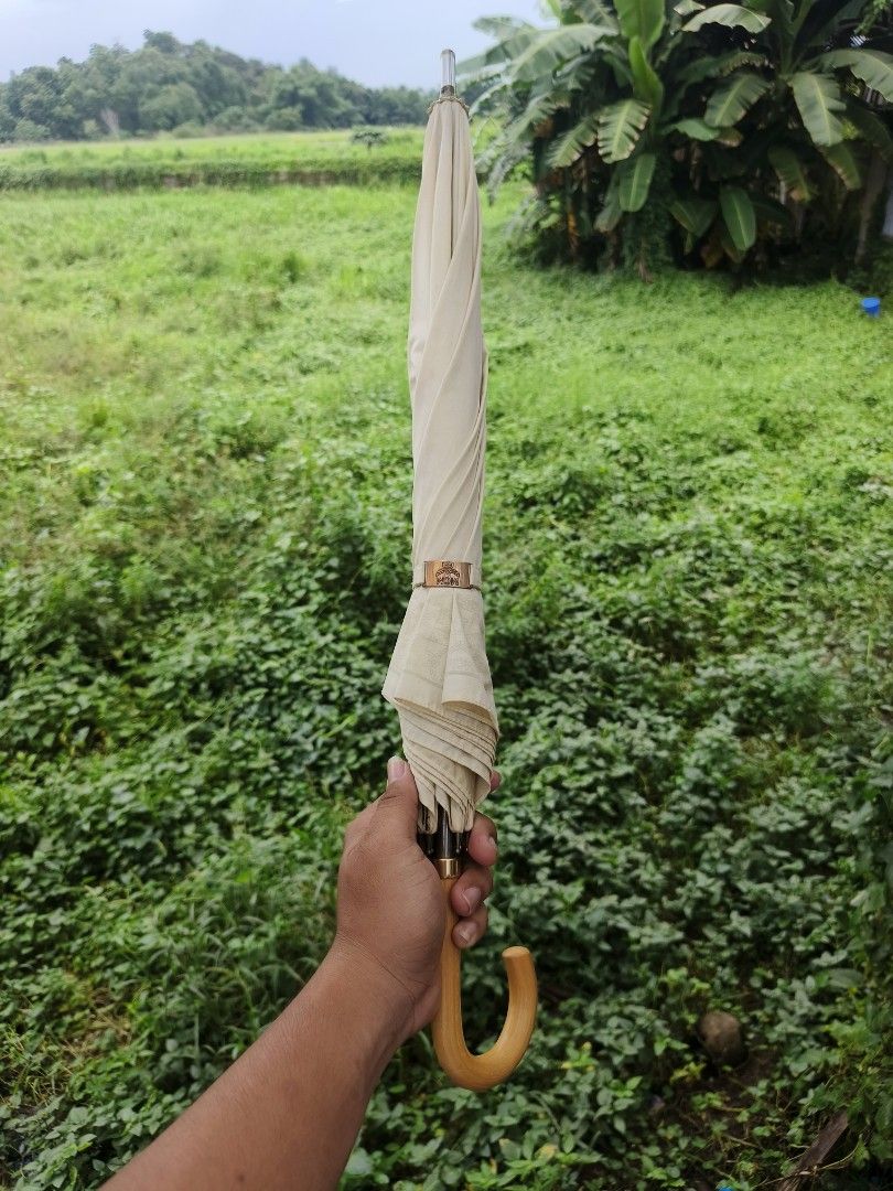 MCM Umbrella White Vintage (Category: Umbrellas) located in Ipil. Submitted by ajthriftfinds (Listing ID 1449408299, Image 3). Description: - Classic white MCM umbrella - Issue, pinhole on picture - Features intricate fabric patterns - Comfortable wooden curved handle - Folds compactly for easy storage - Ideal for both sunny and rainy weather - A chic and stylish accessory.