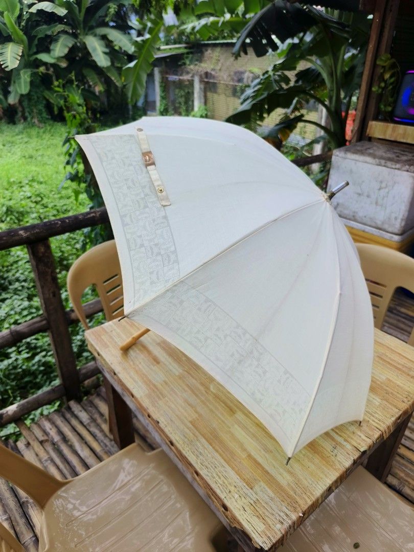 MCM Umbrella White Vintage (Category: Umbrellas) located in Ipil. Submitted by ajthriftfinds (Listing ID 1449408299, Image 2). Description: - Classic white MCM umbrella - Issue, pinhole on picture - Features intricate fabric patterns - Comfortable wooden curved handle - Folds compactly for easy storage - Ideal for both sunny and rainy weather - A chic and stylish accessory.