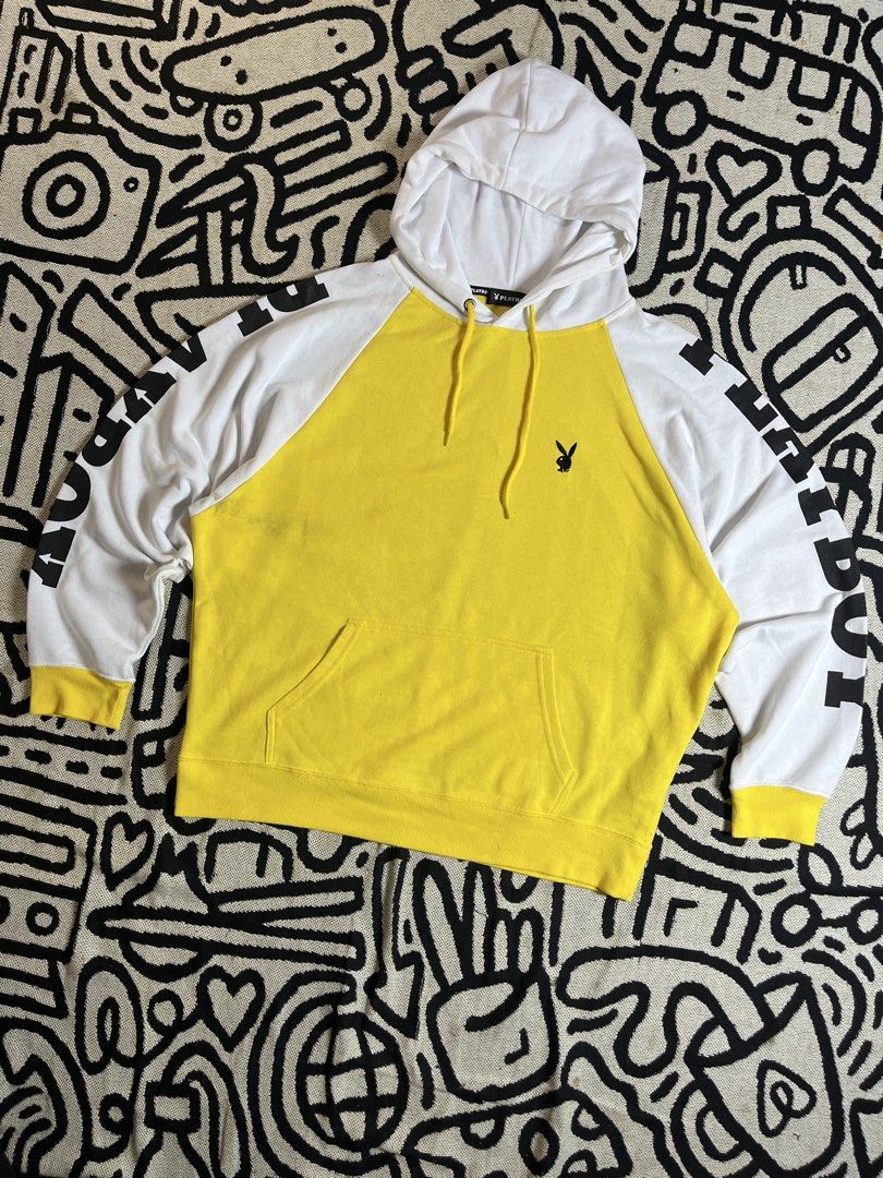 Playboy Yellow & White Raglan Hoodie (Category: Hoodies) located in Silang. Submitted by yusthrift (Listing ID 1449346030, Image 1). Description: - Playboy raglan hoodie in yellow and white. - Features the iconic Playboy bunny logo on the front. - 'PLAYBOY' text graphic printed on the sleeves. - Convenient kangaroo pocket for your essentials. - Adjustable drawstring hood for a comfortable fit. - Ideal for everyday casual wear. Size: L on tag 24.5