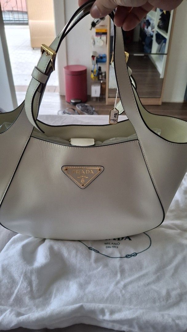 Prada Cream Leather Shoulder Bag with dustbag (Category: Luxury Bags & Wallets) located in Angono. Submitted by bagamania (Listing ID 1449337464, Image 2). Description: - Prada cream leather shoulder bag - Elegant gold hardware details - Adjustable strap with secure buckle closure -100% genuine leather - Iconic Prada triangle logo on the front - Interior buckle closure for added security - Clean and chic design, ideal for daily use.