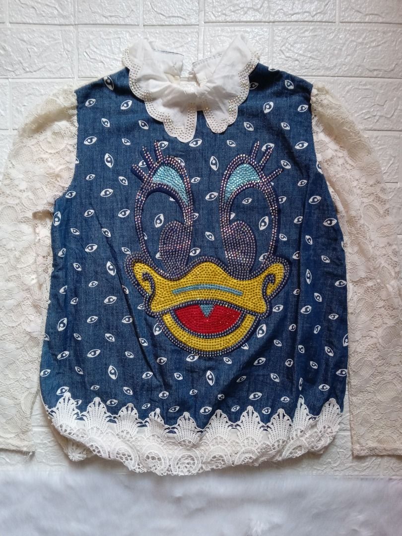 Unique Daisy Duck Sequin Denim Blouse / Statement Lace Long Sleeve Top (Category: Sleeveless) located in Los Banos. Submitted by wise-fox27 (Listing ID 1449398084, Image 1). Description: Description: Condition: Preloved, in excellent condition with vibrant sequins intact. Color: Medium Wash Denim Blue with White Lace details. Style: A stunning, eye-catching piece! Features a soft chambray denim bodice printed with all-over eye shapes and a large,