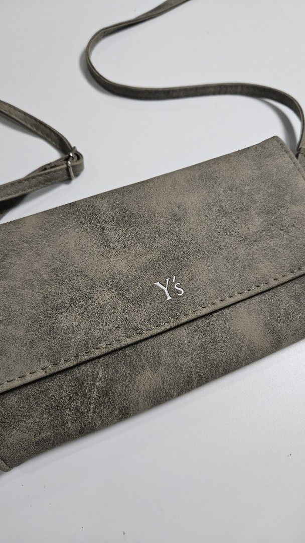 Y’s Yohji Yamamoto Wallet (Category: Luxury Bags & Wallets) located in Alfonso. Submitted by jbcamet (Listing ID 1449488824, Image 2). Description: - Chic grey wallet with distinct YS logo - Versatile long strap for crossbody wear - Interior includes multiple card slots for easy access - Secure zippered compartment for coins or small items - Front snap closure for added security - Ideal for keeping your essentials organized while on the move.