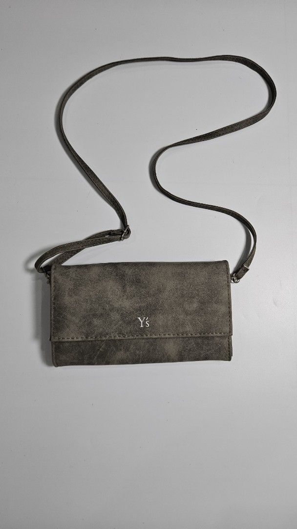 Y’s Yohji Yamamoto Wallet (Category: Luxury Bags & Wallets) located in Alfonso. Submitted by jbcamet (Listing ID 1449488824, Image 1). Description: - Chic grey wallet with distinct YS logo - Versatile long strap for crossbody wear - Interior includes multiple card slots for easy access - Secure zippered compartment for coins or small items - Front snap closure for added security - Ideal for keeping your essentials organized while on the move.