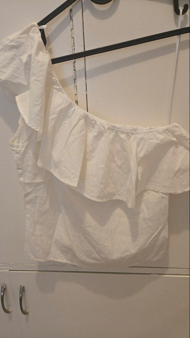 Bershka White One Shoulder Ruffle Crop Top (Category: Sleeveless) located in Manila. Submitted by xiaauma (Listing ID 1449626418, Image 1). Description: - Bershka white one-shoulder crop top - Features a ruffled overlay on the front - Elasticated hem and neckline for comfort - Made in Morocco - Versatile for casual outings or nights out.