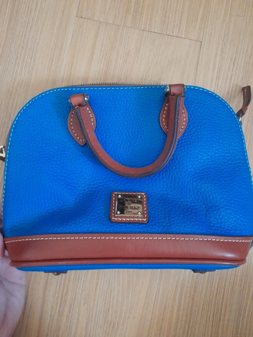 Dooney & Bourke Blue Leather Satchel Handbag (Category: Luxury Bags & Wallets) located in Angeles City. Submitted by declutterhub (Listing ID 1449651506, Image 1). Description: Classic blue leather satchel with brown trim. Features top handles, detachable strap, zip closure, and interior pockets. Gold-tone hardware. small size..