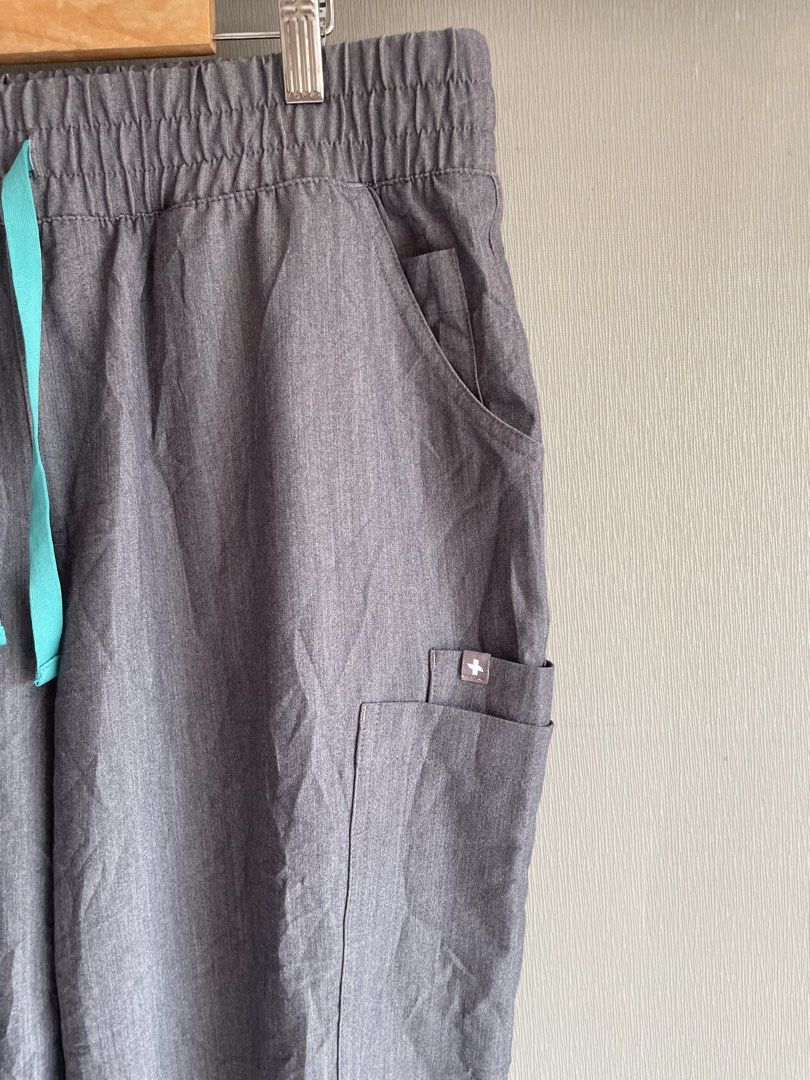 FIGS Technical Collection Scrub Pants L/P Grey (Category: Other Bottoms) located in Mataasnakahoy. Submitted by zero4thrift (Listing ID 1449589132, Image 2). Description: These are FIGS Yola skinny scrub pants in a gray shade with an aqua drawstring. - Size: L/P - Collection: Technical - Material: Polyester, Rayon, Spandex blend - Features: Comfortable elastic waistband with drawstring, multiple pockets including a zippered pocket - Ideal for: He