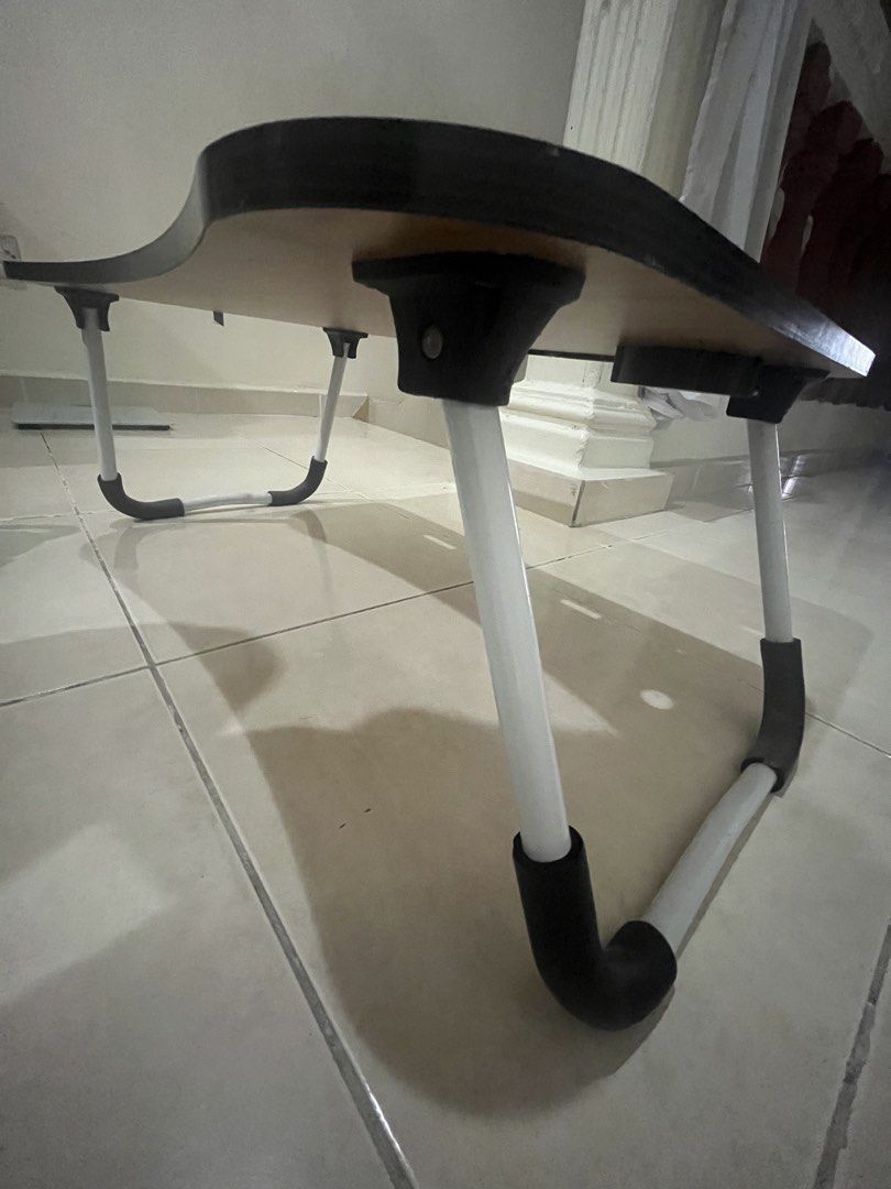 Foldable Table (Category: Tables & Sets) located in Bangi. Submitted by ainshukri (Listing ID 1449603049, Image 2). Description: - Portable laptop table, ideal for bed use. - Built-in cup holder and tablet/phone slot. - Legs fold flat for convenient storage. - Stylish dark wood grain finish. - Space-saving design, perfect for small homes..