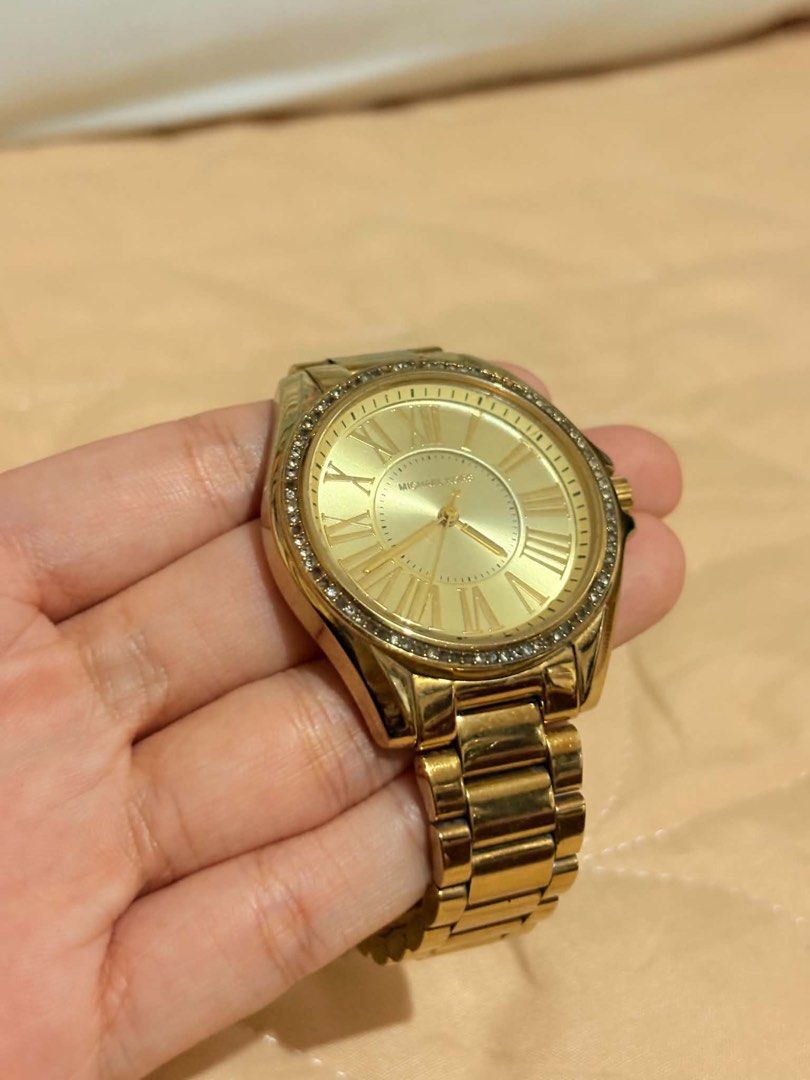 Michael Kors Gold Watch with Crystal Bezel (Category: Women's Watches) located in Cavite. Submitted by jeangerbreadgirl (Listing ID 1449665695, Image 2). Description: - Authentic Michael Kors watch - Elegant gold-tone finish - Roman numeral dial - Sparkling crystal accents on bezel - Durable stainless steel band and clasp - Clasp features Michael Kors logo - Shows some signs of normal wear on band and case - Requires a new battery.