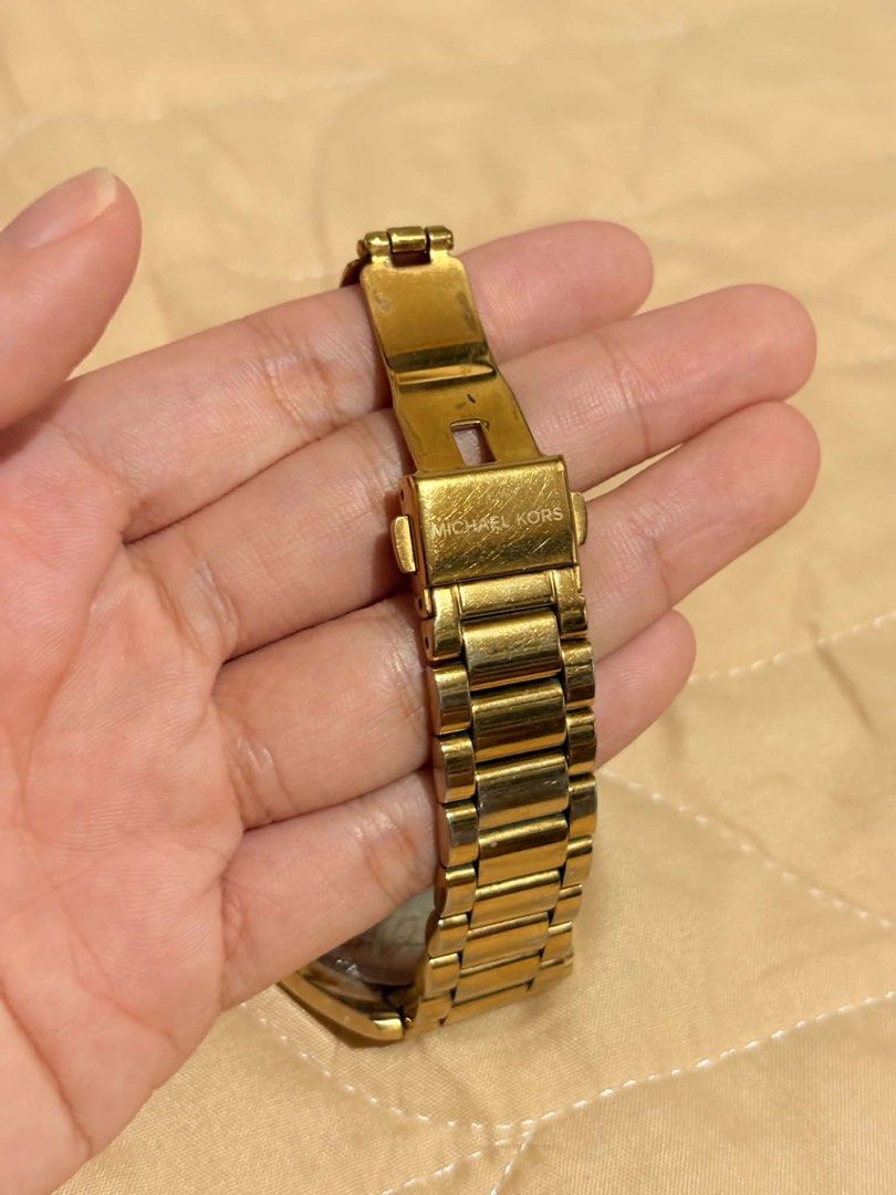 Michael Kors Gold Watch with Crystal Bezel (Category: Women's Watches) located in Cavite. Submitted by jeangerbreadgirl (Listing ID 1449665695, Image 3). Description: - Authentic Michael Kors watch - Elegant gold-tone finish - Roman numeral dial - Sparkling crystal accents on bezel - Durable stainless steel band and clasp - Clasp features Michael Kors logo - Shows some signs of normal wear on band and case - Requires a new battery.
