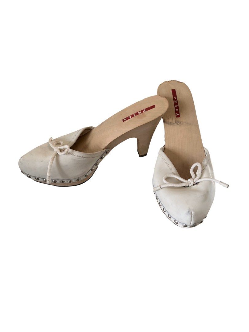 Prada White Leather Wood Heel Mules Clogs Size 37 (Category: Sneakers & Footwear) located in Manila. Submitted by slavetorave (Listing ID 1449648102, Image 3). Description: - White leather mules - Wooden heel - Cute bow detail on front - Studded trim around sole - Made in Italy - Size 37 - scuffs on wood and leather (expected wear) -Leather needs to be cleaned and there are some chips on the wooden sole (see pictures) .