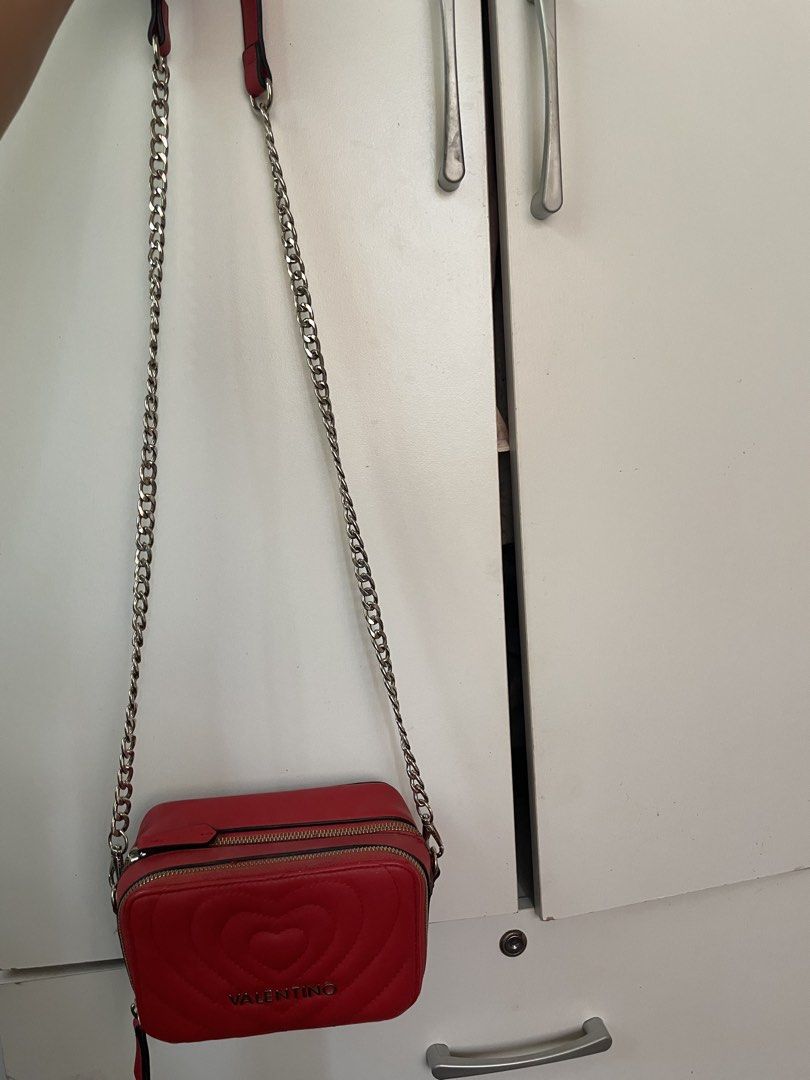 Red Valentino Heart Quilted Camera Bag (Category: Luxury Bags & Wallets) located in Baao. Submitted by closetbykb (Listing ID 1449556315, Image 3). Description: - Adorable red Valentino bag with a charming heart design. - Features a sleek silver chain strap. - Convenient zip pocket on the back for quick access. - Secure main zip compartment inside. - Interior includes a small leather tag with the Valentino logo. - Ideal size for carrying your dai
