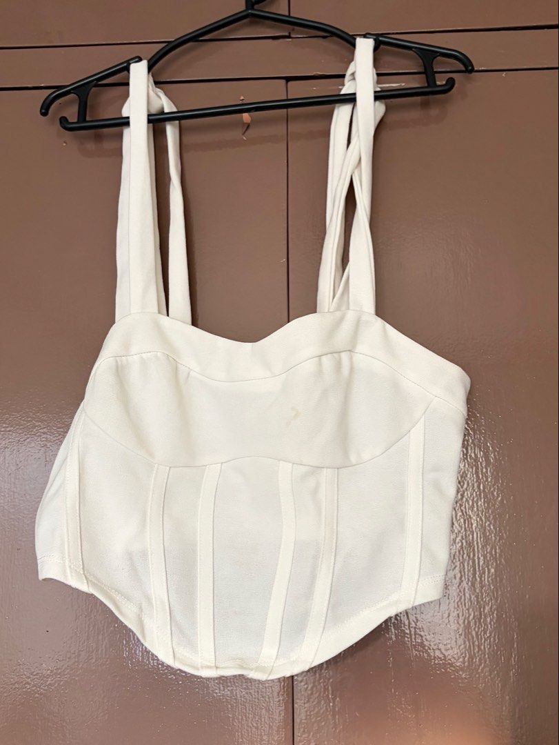 SHEIN White Corset Top with Tie Straps (Category: Sleeveless) located in Quezon City. Submitted by crystalivory (Listing ID 1449633042, Image 1). Description: - White corset top from SHEIN - Features adjustable tie-up straps - Structured bodice with boning for a flattering fit - Versatile: pairs well with jeans or skirts - Comfortable and stylish for any occasion - stain on chest area but removable.