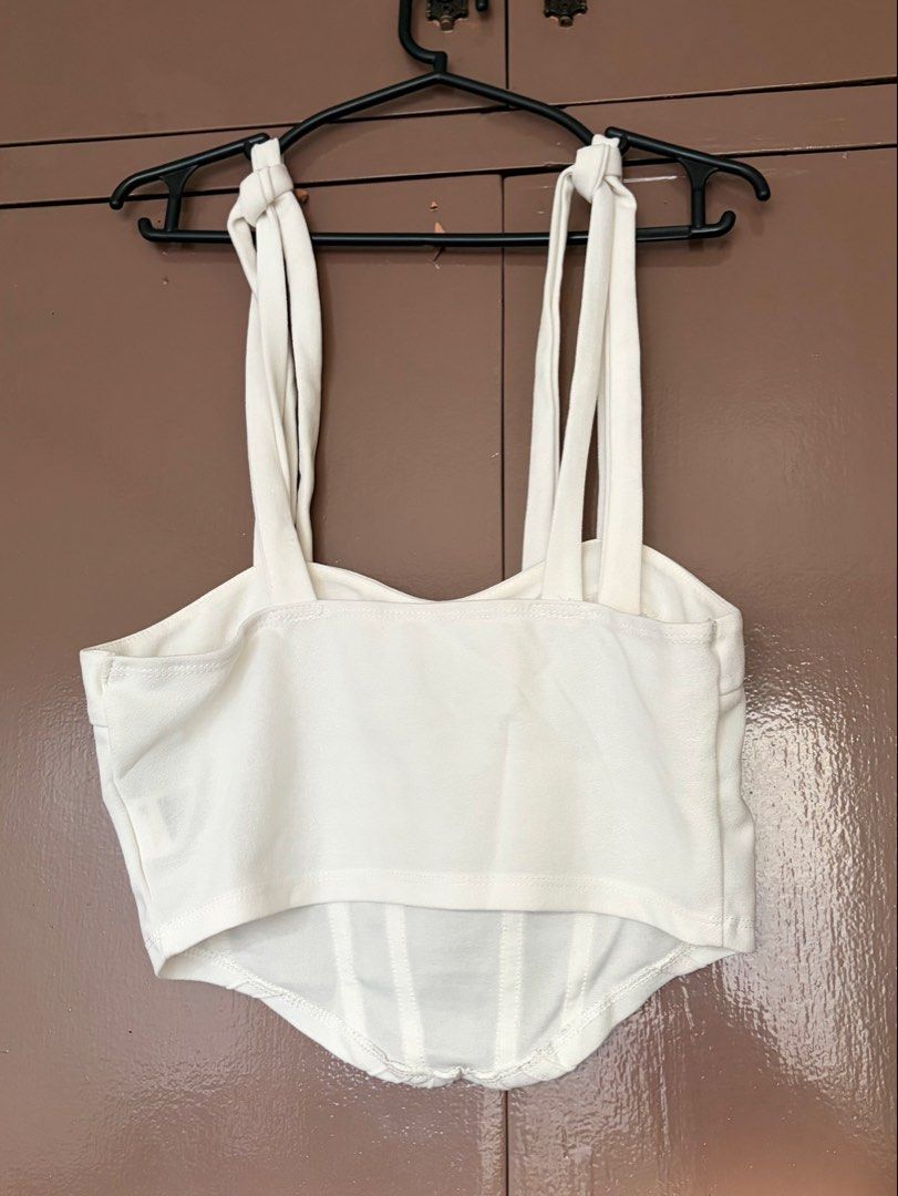SHEIN White Corset Top with Tie Straps (Category: Sleeveless) located in Quezon City. Submitted by crystalivory (Listing ID 1449633042, Image 2). Description: - White corset top from SHEIN - Features adjustable tie-up straps - Structured bodice with boning for a flattering fit - Versatile: pairs well with jeans or skirts - Comfortable and stylish for any occasion - stain on chest area but removable.