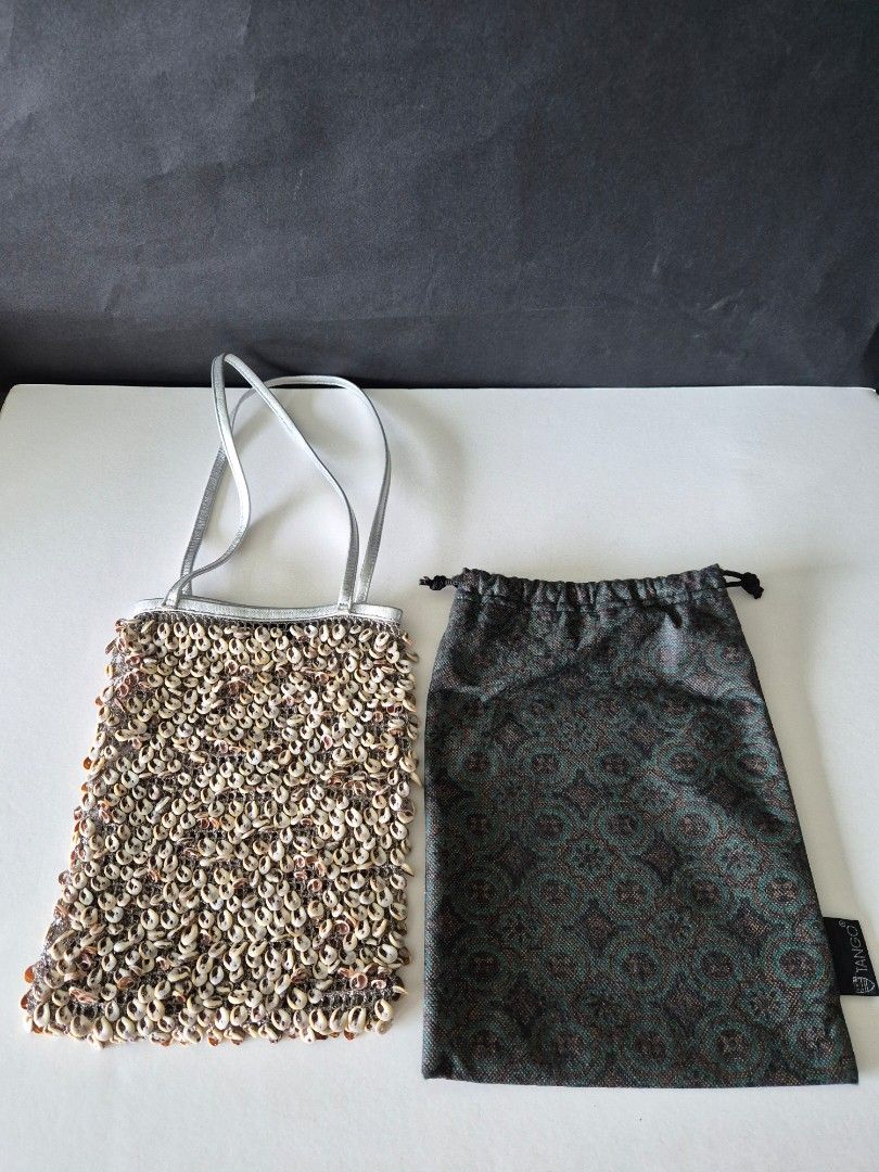 Tango Drawstring Pouch with Pattern (Category: Purses & Pouches) located in Singapore. Submitted by clunar (Listing ID 1449604747, Image 2). Description: - This Tango bag adorned with numerous small white seashells, with a thin silver shoulder strap - Includes a drawstring dark green pattern fabric bag, tag with 'TANGO' logo. - The fabric bag can be use as a drawstring bucket bag or dustbag when storing - Perfect for weekends, casual and stylish 