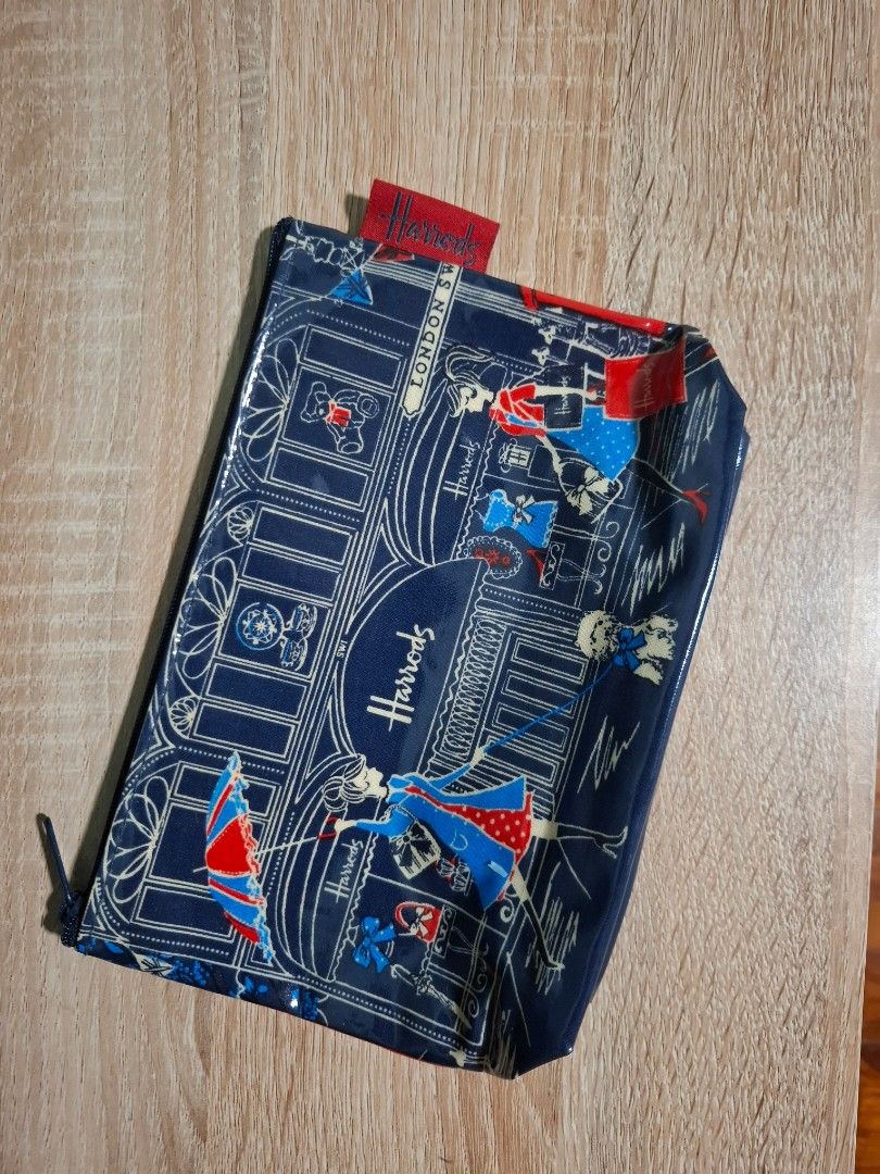 Harrods London Blue Cosmetic Pouch (Category: Purses & Pouches) located in Makati City. Submitted by itemsforless2025 (Listing ID 1449897743, Image 2). Description: - Cute Harrods pouch with a charming London scene print. - Features women shopping and iconic London landmarks. - Secure zip closure. -pvc material - Ideal for storing makeup or travel essentials. - Approximate dimensions: 8 inches wide x 5 inches tall. - Interior lining also features