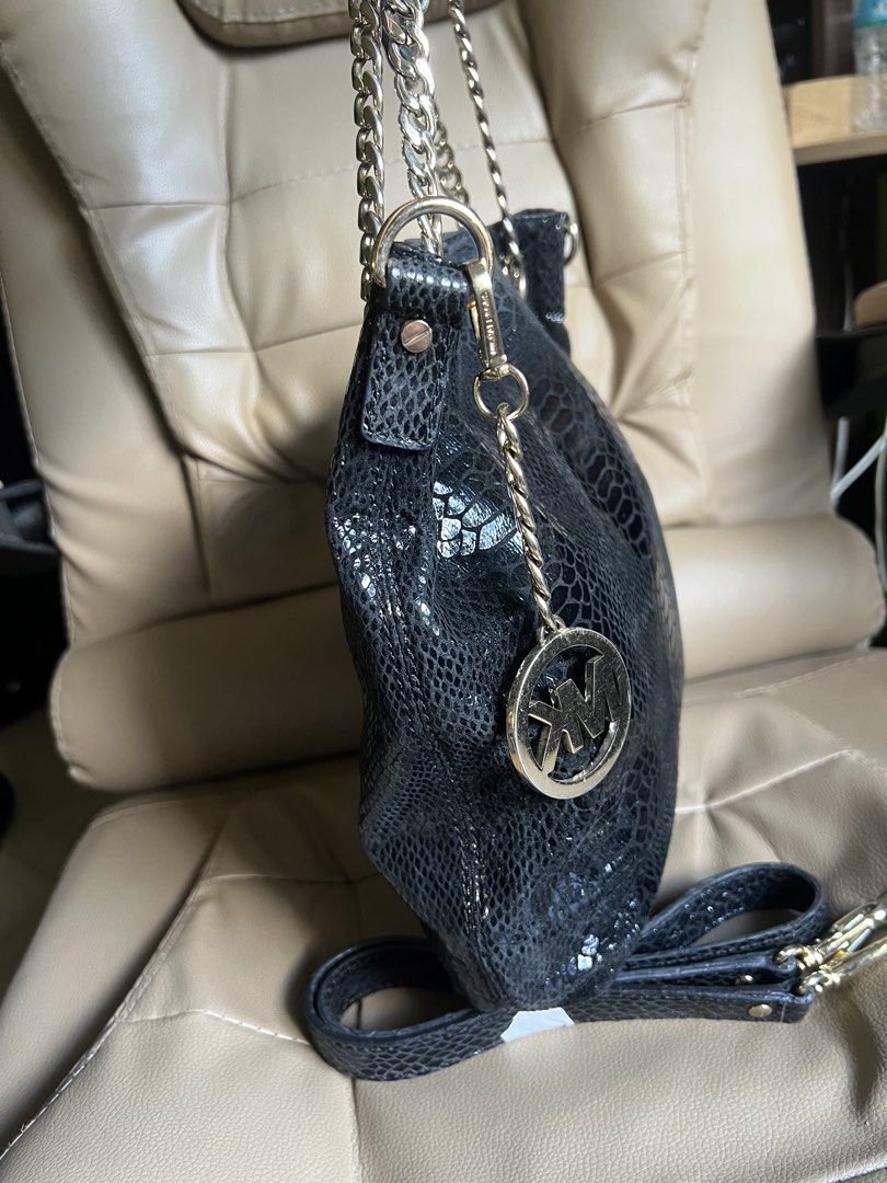Michael Kors Black Snakeskin Leather Chain Shoulder Bag (Category: Luxury Bags & Wallets) located in Saravia. Submitted by clynlyn (Listing ID 1449820522, Image 2). Description: - Black Michael Kors shoulder bag - Snakeskin texture - Gold chain straps - Gold MK charm - Detachable crossbody strap included - Interior MK logo lining - Inner zip pocket - Versatile for everyday or evening wear.