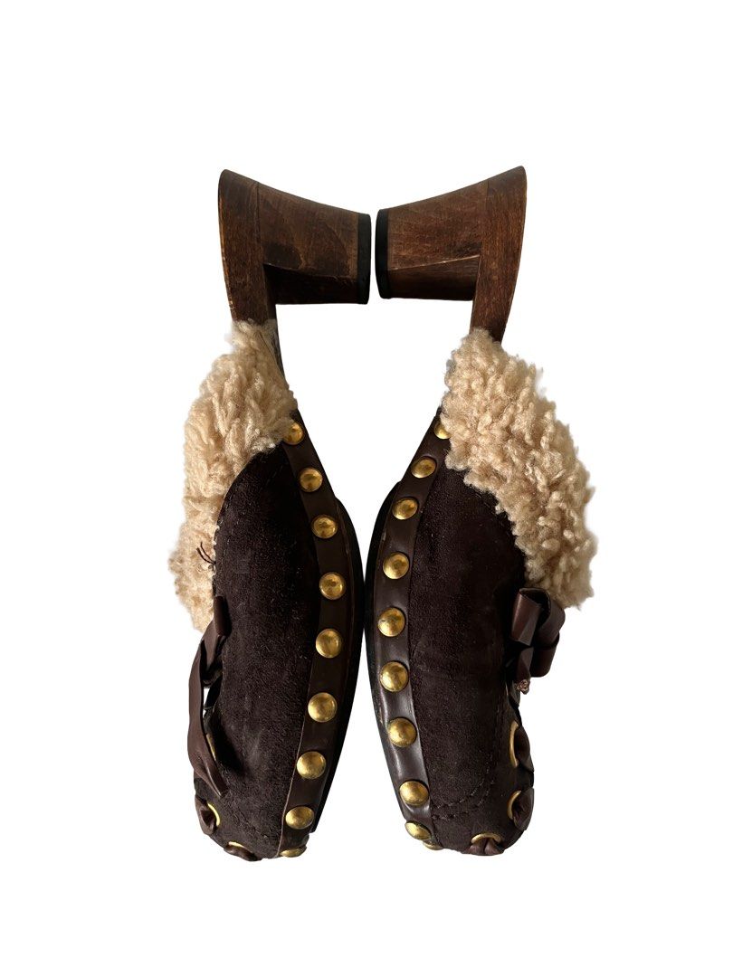 Miu Miu Brown Suede Shearling Clogs Mules Size 37 (Category: Loafers) located in Manila. Submitted by slavetorave (Listing ID 1449812857, Image 2). Description: - Luxurious brown suede mules - Soft shearling trim for ultimate comfort - Stylish wooden heel and sole - Elegant front lace-up detail with ribbon ties - Chic gold stud accents around the sole - Authentic Made in Italy craftsmanship - Size 37.