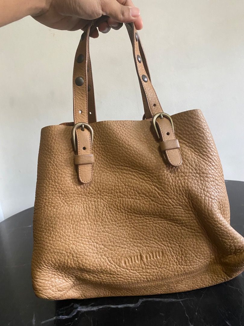 Miu Miu Leather Tote Bag (Category: Luxury Bags & Wallets) located in Manila. Submitted by haveago0dthrift (Listing ID 1449818668, Image 1). Description: - Authentic Miu Miu tan leather tote bag - Pebbled leather texture - Buckle details on straps - Interior zippered pocket - Minor signs of wear on leather and hardware - Made in Italy.