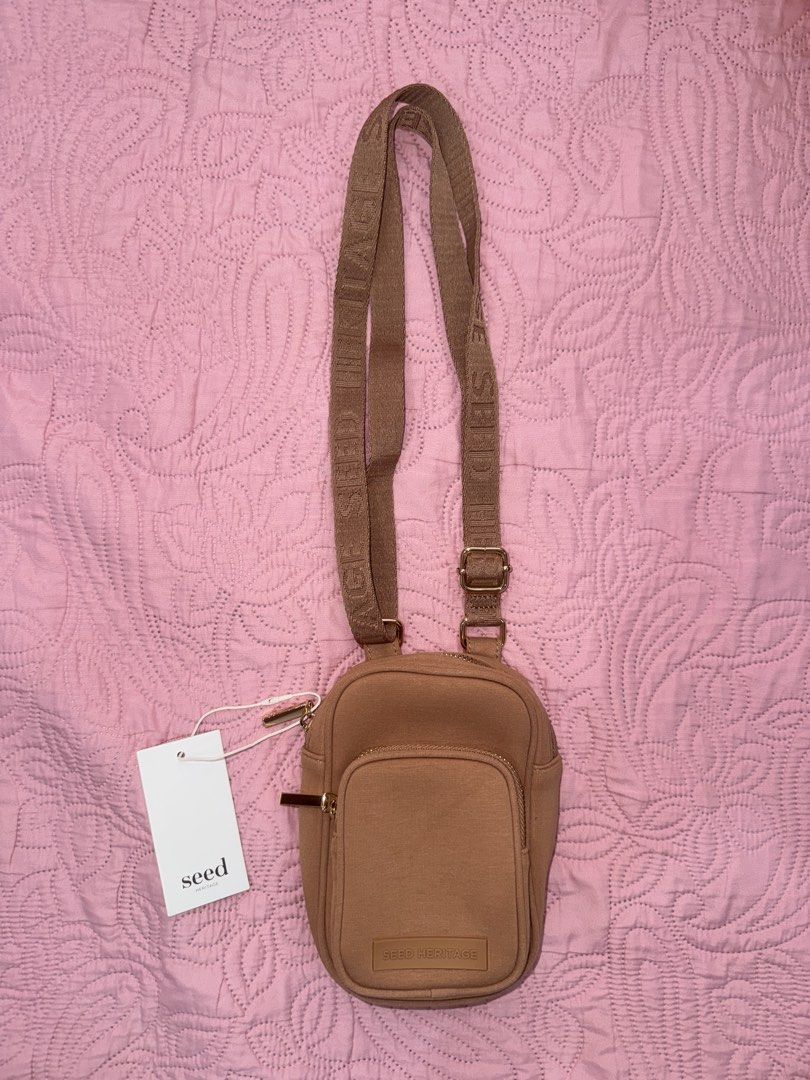 SEED HERITAGE Tan Jersey Crossbody Bag (Category: Cross-body Bags) located in Manila. Submitted by decluterrrr (Listing ID 1449778140, Image 3). Description: Dimensions: 11.5 x 18 x 4.5cm Fabrication: Body: 70% Cotton, 30% Polyurethane Compact and ideal for keeping your essentials at hand, this bag features a logo-branded crossbody strap, an internal slip pocket, an external front pocket, and zip closures. Features: Crossbody strap with logo Zip 