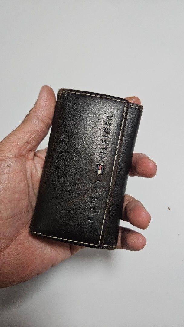 Tommy Hilfiger Leather Key Holder Wallet (Category: Wallets & Card holders) located in Alfonso. Submitted by jbcamet (Listing ID 1449852405, Image 2). Description: - Authentic Tommy Hilfiger key holder - Made from premium dark brown leather - Features multiple key hooks for organization - Includes a convenient small slot for cards or cash - Secure snap button closure - Classic and timeless design.
