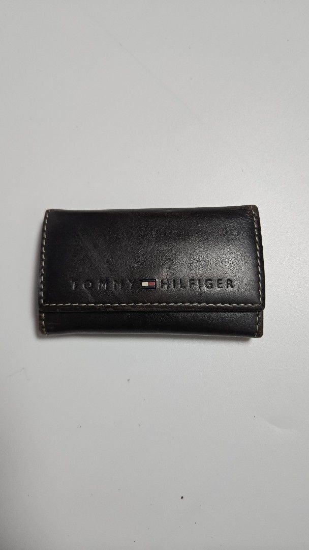 Tommy Hilfiger Leather Key Holder Wallet (Category: Wallets & Card holders) located in Alfonso. Submitted by jbcamet (Listing ID 1449852405, Image 1). Description: - Authentic Tommy Hilfiger key holder - Made from premium dark brown leather - Features multiple key hooks for organization - Includes a convenient small slot for cards or cash - Secure snap button closure - Classic and timeless design.
