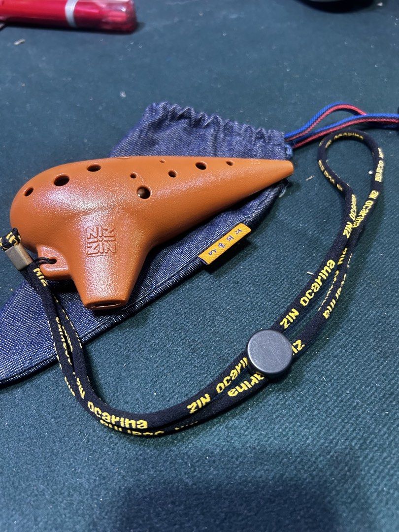 ZIN Ocarina with Pouch and Lanyard (Category: Musical Instruments) located in Manila. Submitted by starbalesukandjapansurplus (Listing ID 1449832050, Image 1). Description: - Brown 12-hole ocarina - Features 'NIZ ZIN' logo - Comes with a denim pouch - Includes a black lanyard with 'ZIN ocarina' print - Ideal for beginners and collectors - Easy to carry around.