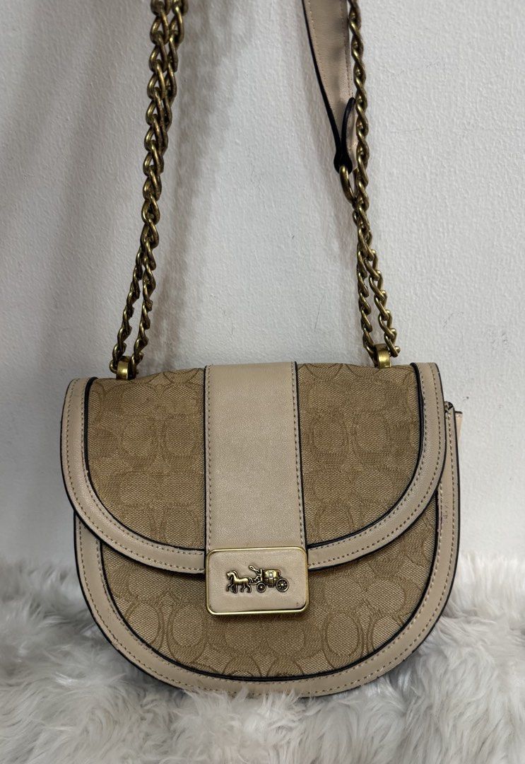 Coach Signature Canvas Saddle Bag (Category: Luxury Bags & Wallets) located in Malolos. Submitted by urban_thrift_09 (Listing ID 1450101954, Image 2). Description: - Authentic Coach saddle bag - Color: Tan and beige signature canvas with leather trim - Hardware: Gold chain strap and horse and carriage logo - Interior: Coach creed patch and smaller tag - Size: 8”x 7.5”x 3”.