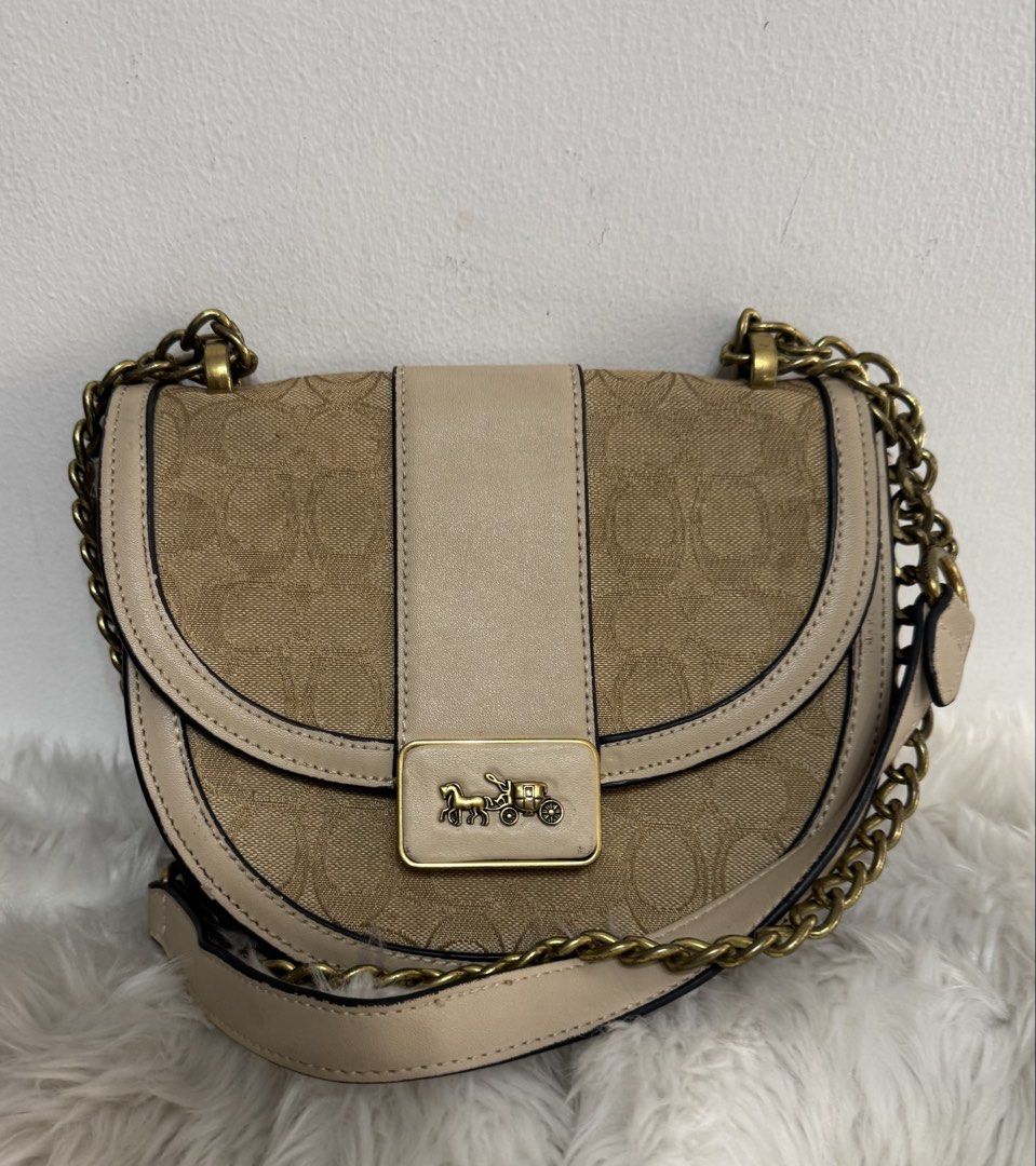 Coach Signature Canvas Saddle Bag (Category: Luxury Bags & Wallets) located in Malolos. Submitted by urban_thrift_09 (Listing ID 1450101954, Image 1). Description: - Authentic Coach saddle bag - Color: Tan and beige signature canvas with leather trim - Hardware: Gold chain strap and horse and carriage logo - Interior: Coach creed patch and smaller tag - Size: 8”x 7.5”x 3”.