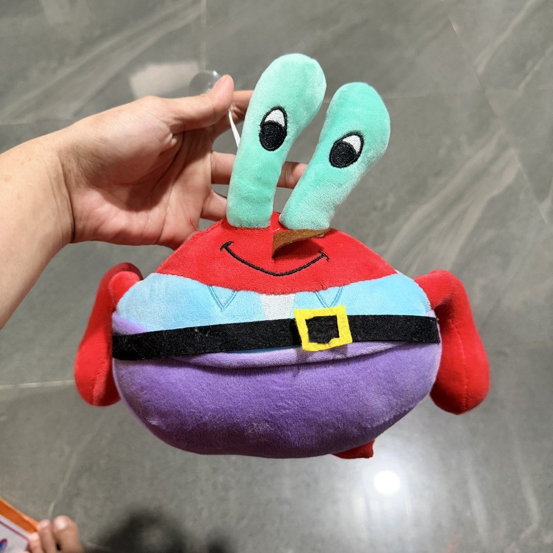 SpongeBob SquarePants Mr. Krabs Plush Toy (Category: Plushies & Soft Toys) located in Quezon City. Submitted by ThirftyClub (Listing ID 1449953160, Image 1). Description: - Authentic Mr. Krabs plush toy from SpongeBob SquarePants. - Features a vibrant red crab design with light blue and purple accents. - Includes his iconic signature belt. - Stands approximately 6-7 inches tall. - Comes with a convenient suction cup and string attached to the top