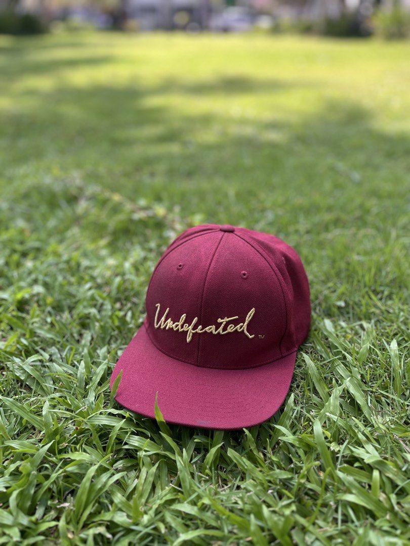 Undefeated Burgundy Corduroy Snapback Hat (Category: Caps & Hats) located in Bulacan. Submitted by sef19 (Listing ID 1449961724, Image 2). Description: - Burgundy corduroy snapback from Undefeated - Gold embroidered 'Undefeated' script on the front - Small gold '5 strikes' logo on the back - Adjustable snap closure for a custom fit - Crafted from a comfortable acrylic and wool blend.