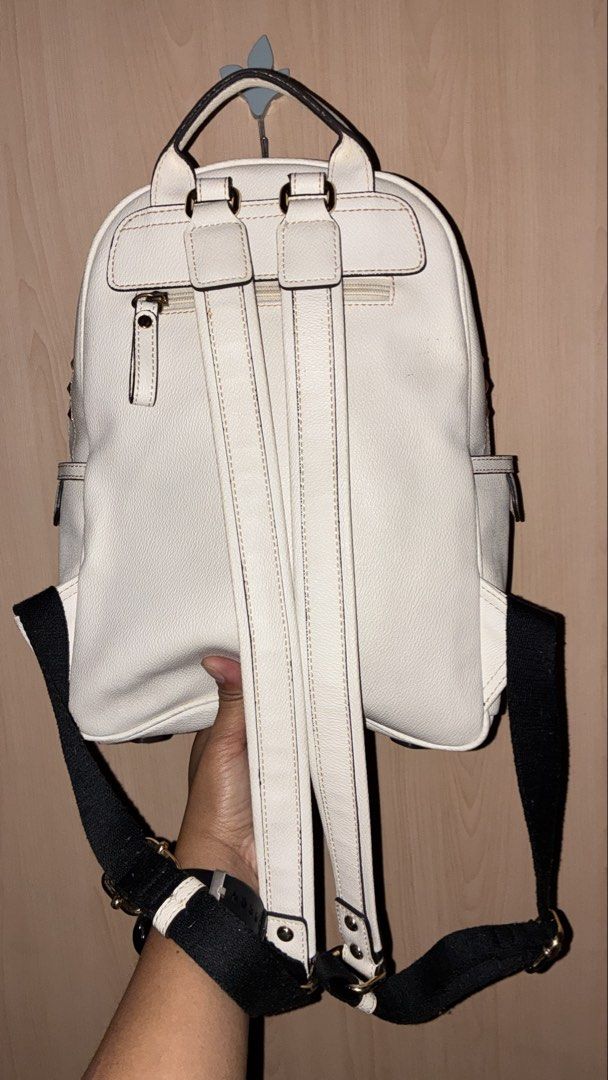 White Studded Backpack with 'E' Initial (Category: Backpacks) located in Placer. Submitted by talaalond61563 (Listing ID 1449954381, Image 2). Description: - E-LAND - Stylish white backpack with eye-catching gold studs. - Convenient front zip pocket and side pockets for organization. - Features a unique 'E' detail on the front. - Adjustable black straps with white stripes for a comfortable fit. - Ideal for everyday use, school, or travel..