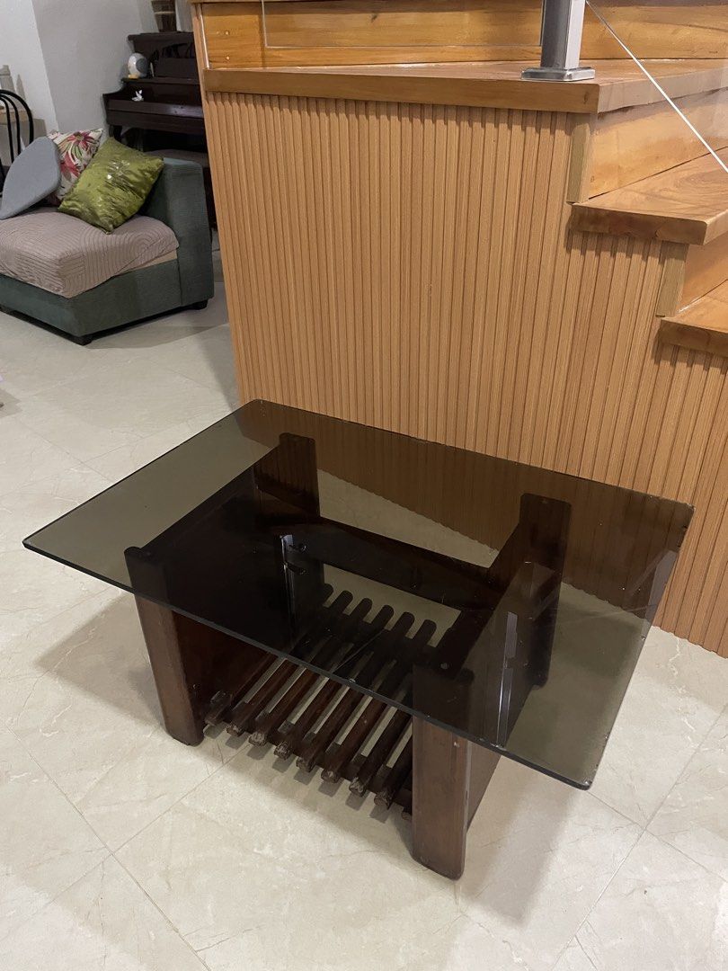 Wooden and Glass Center Table (Category: Tables & Sets) located in Manila. Submitted by shaneacara (Listing ID 1449957565, Image 1). Description: - Rectangular coffee table - Dark wood base with slatted shelf for storage - Glass top - Scratches and chips on glass edges but rest assured that glass is thick and no other flaws.