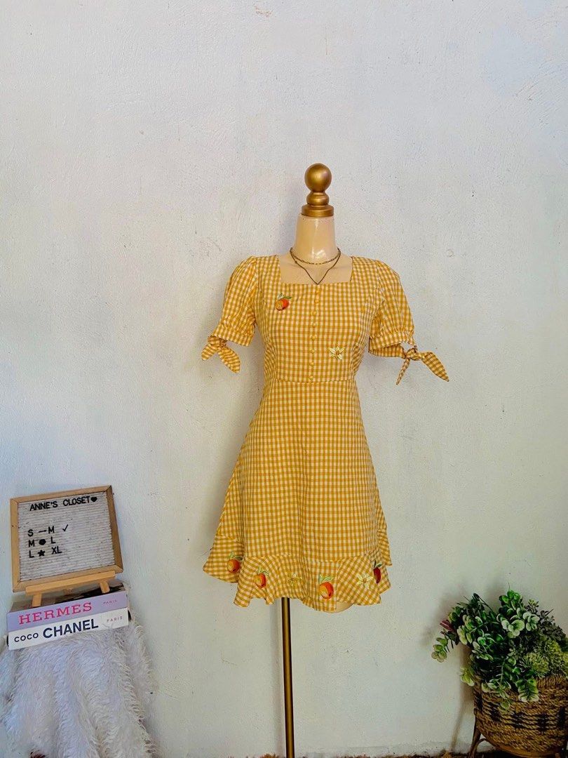Yellow Gingham Dress with Peach Embroidery (Category: Dresses) located in Meycauayan. Submitted by twinblessing (Listing ID 1450068331, Image 1). Description: - Adorable yellow gingham dress - Features puff sleeves with tie details - Sweet peach embroidery along the hemline - Classic square neckline with button-down front - Ideal for picnics and casual summer days - Offers a sweet and summery vibe.