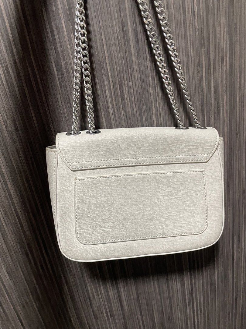 Charles & Keith White Leather Chain Crossbody Bag (Category: Cross-body Bags) located in Caloocan City. Submitted by chraefm (Listing ID 1450162980, Image 2). Description: - White leather crossbody bag by Charles & Keith - Features a chic silver chain strap - Secure flap closure with a metal clasp - Convenient back pocket for easy access - Shows minor signs of wear on the back pocket area - Ideal for casual outings and everyday style with dust ba