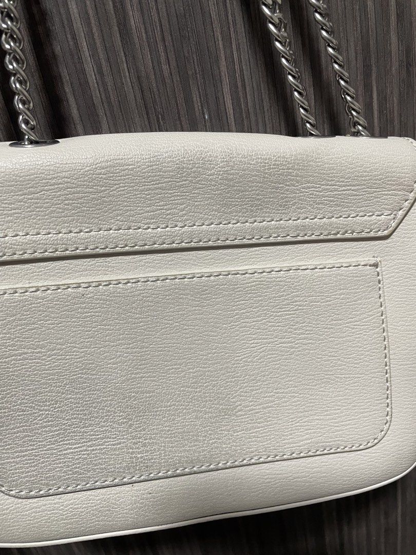 Charles & Keith White Leather Chain Crossbody Bag (Category: Cross-body Bags) located in Caloocan City. Submitted by chraefm (Listing ID 1450162980, Image 3). Description: - White leather crossbody bag by Charles & Keith - Features a chic silver chain strap - Secure flap closure with a metal clasp - Convenient back pocket for easy access - Shows minor signs of wear on the back pocket area - Ideal for casual outings and everyday style with dust ba