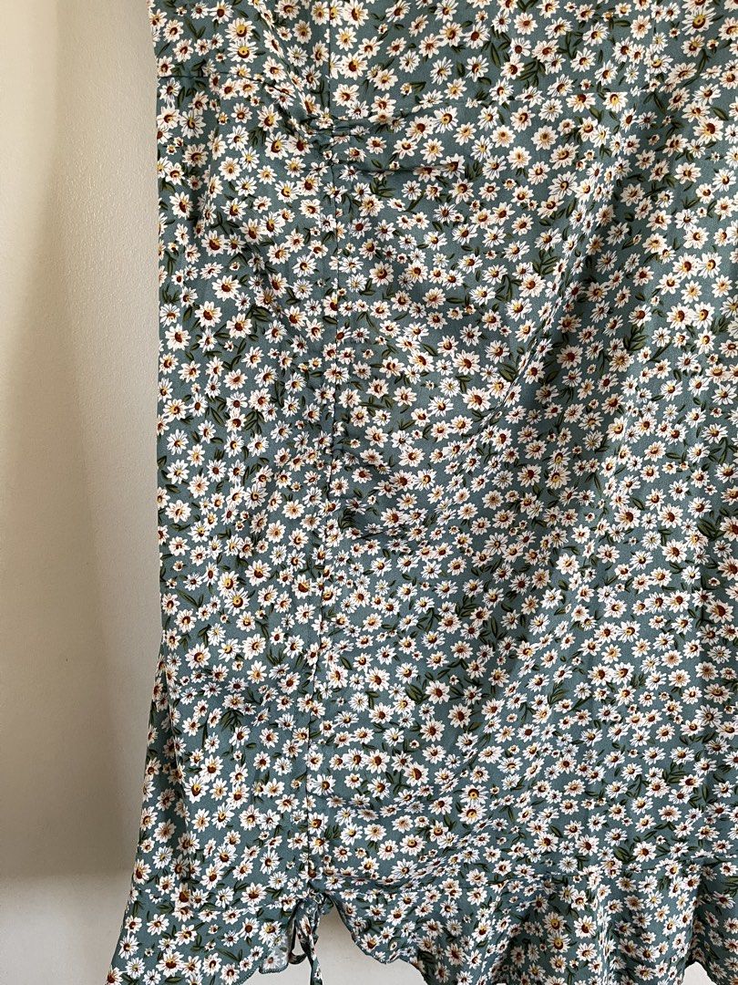 Daisy Print Ruched Midi Dress (Category: Dresses) located in Paombong. Submitted by declutteredbychee_ (Listing ID 1450227069, Image 2). Description: - Green midi dress with a charming white daisy print. - Features short sleeves for comfortable wear. - Flattering ruched detail along the side with a tie at the hem. - Stylish ruffle hemline. - Estimated size: Large (L). - Ideal for casual occasions and everyday style..