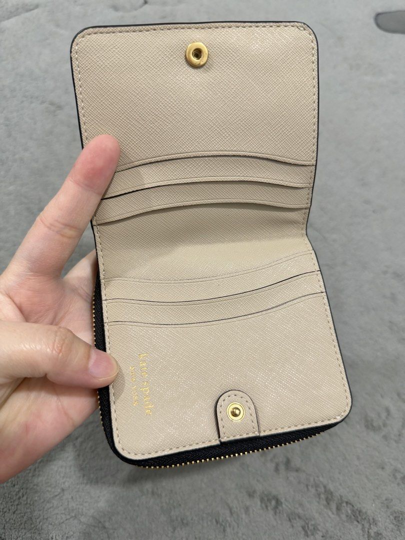 Kate Spade New York Bi-Fold Wallet (Category: Wallets & Card holders) located in Manila. Submitted by moobrava (Listing ID 1450245510, Image 2). Description: - Authentic Kate Spade New York wallet - Stylish beige and black color block design - Convenient bi-fold style with secure snap closure - Interior features multiple card slots and a zippered pocket for essentials - Elegant gold hardware details - Compact and practical for daily use.