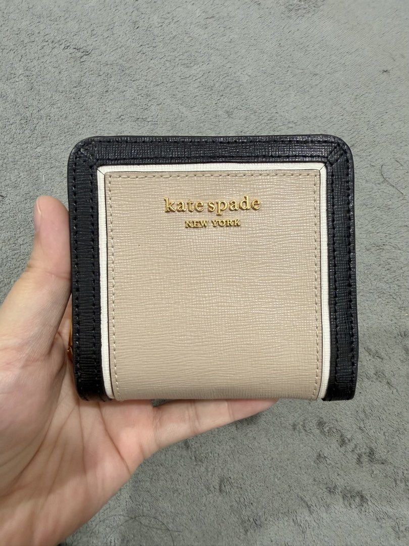 Kate Spade New York Bi-Fold Wallet (Category: Wallets & Card holders) located in Manila. Submitted by moobrava (Listing ID 1450245510, Image 1). Description: - Authentic Kate Spade New York wallet - Stylish beige and black color block design - Convenient bi-fold style with secure snap closure - Interior features multiple card slots and a zippered pocket for essentials - Elegant gold hardware details - Compact and practical for daily use.